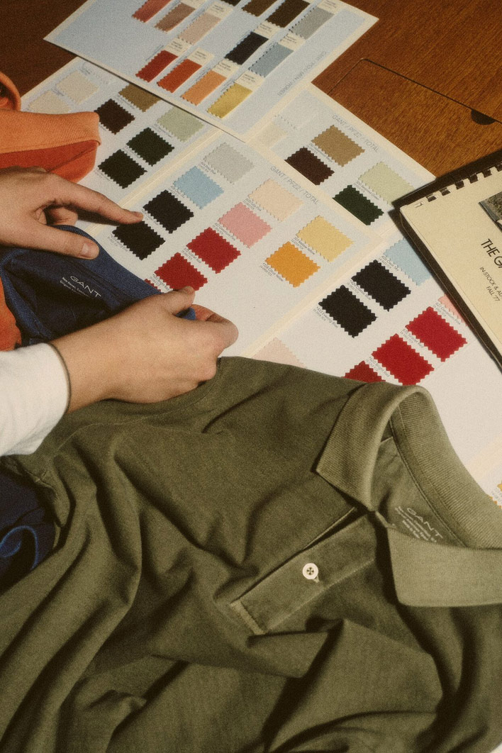 Mani che ordinano polo Gant accanto a una tabella di campioni di colore.