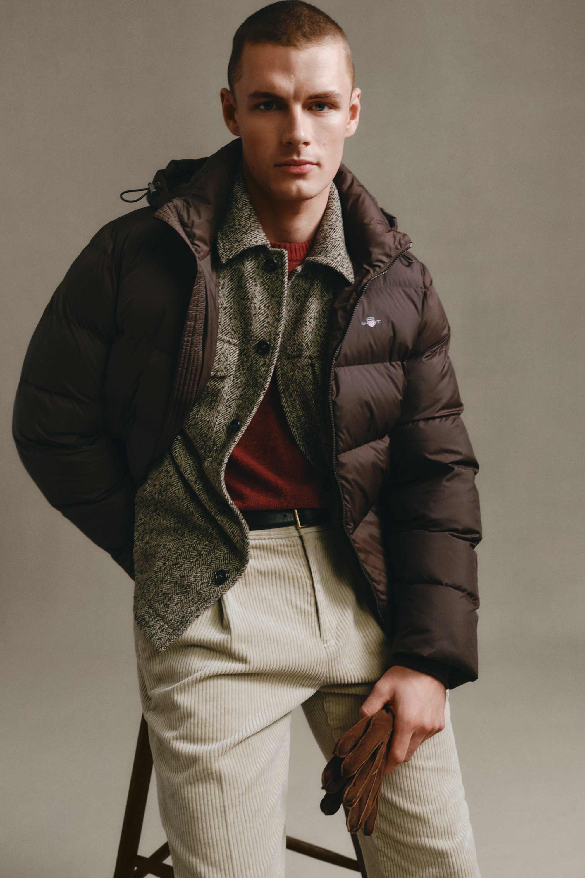 Model styled in a Gant puffer jacket layered over a herringbone overshirt and knit sweater, paired with corduroy pants.