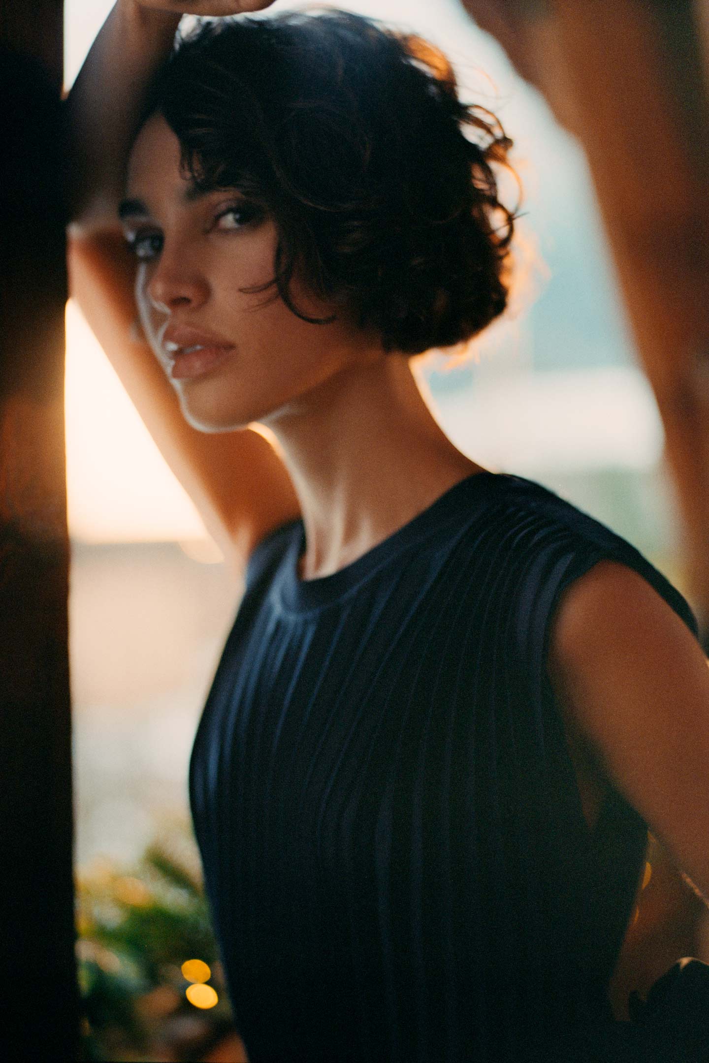 Close up of model styled in a Gant sleeveless pleated midi dress.
