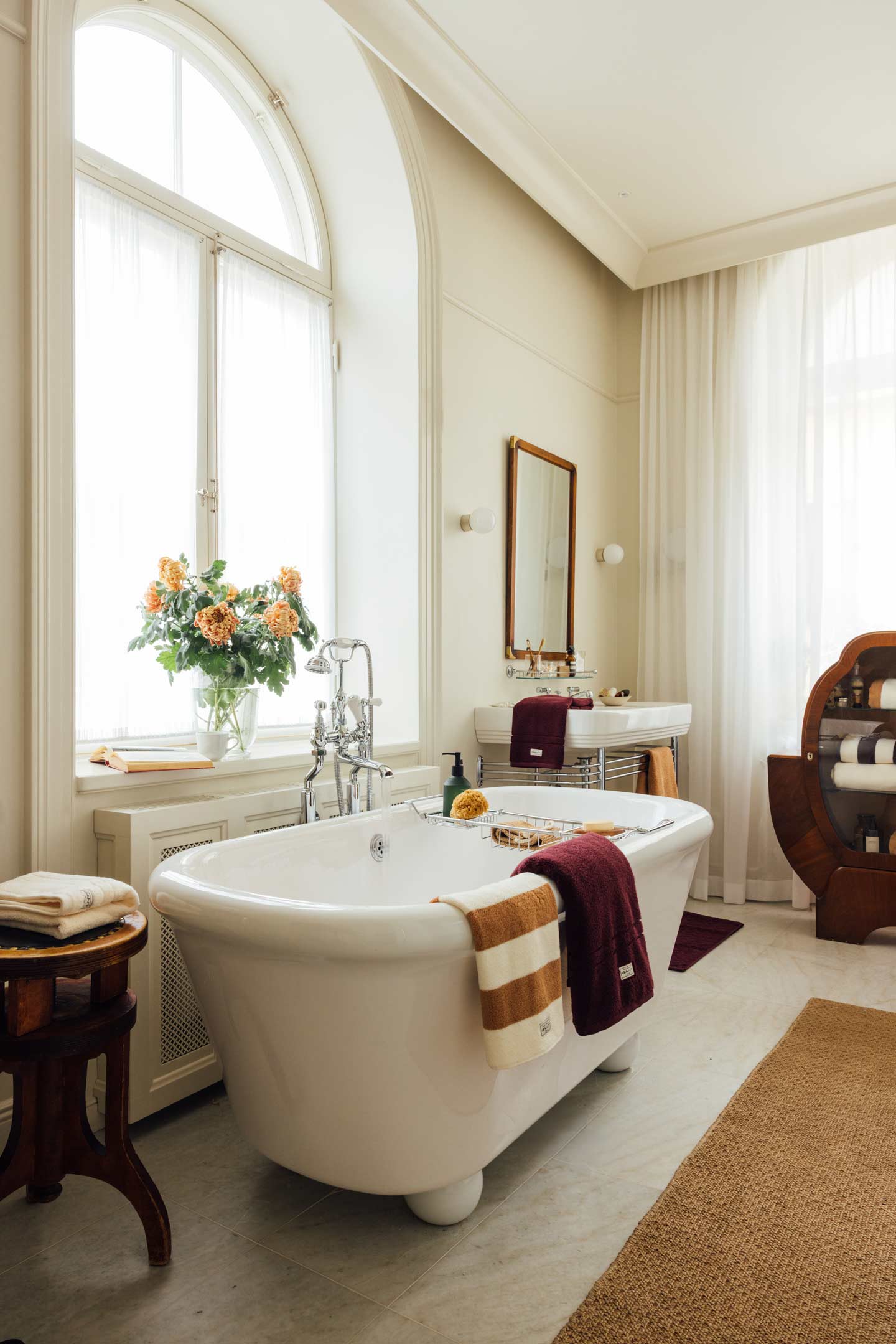 Gant bath towels and robe displayed around a freestanding bathtub in a bright bathroom interior.