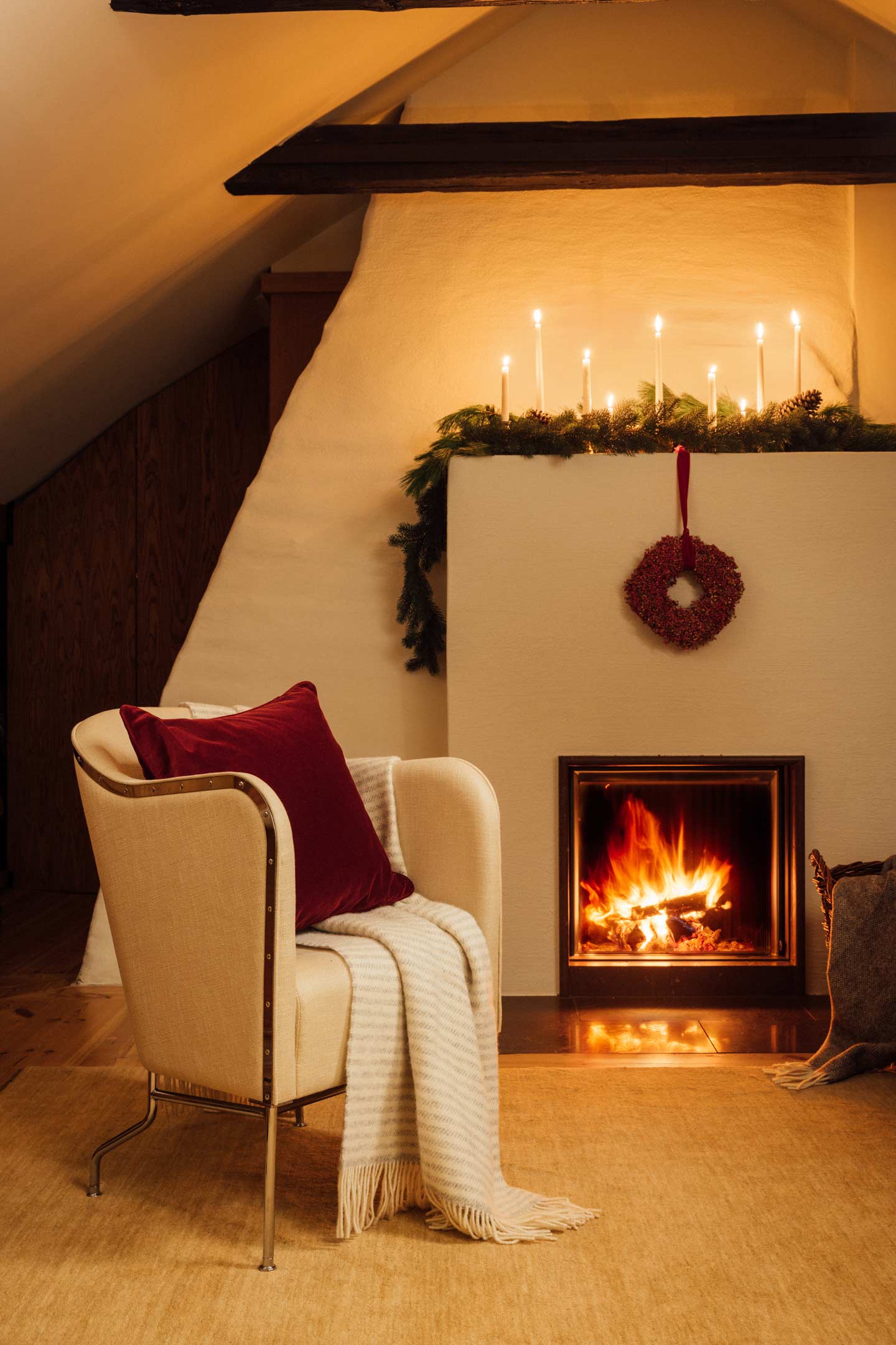 Gant striped throw draped over an armchair beside a lit fireplace in a cosy interior.