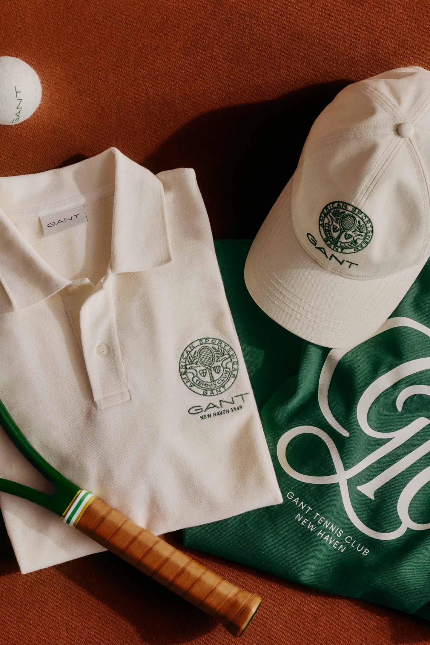 Tennis merchandise including green sweatshirt, white polo shirt, cap, racket, and tennis balls.