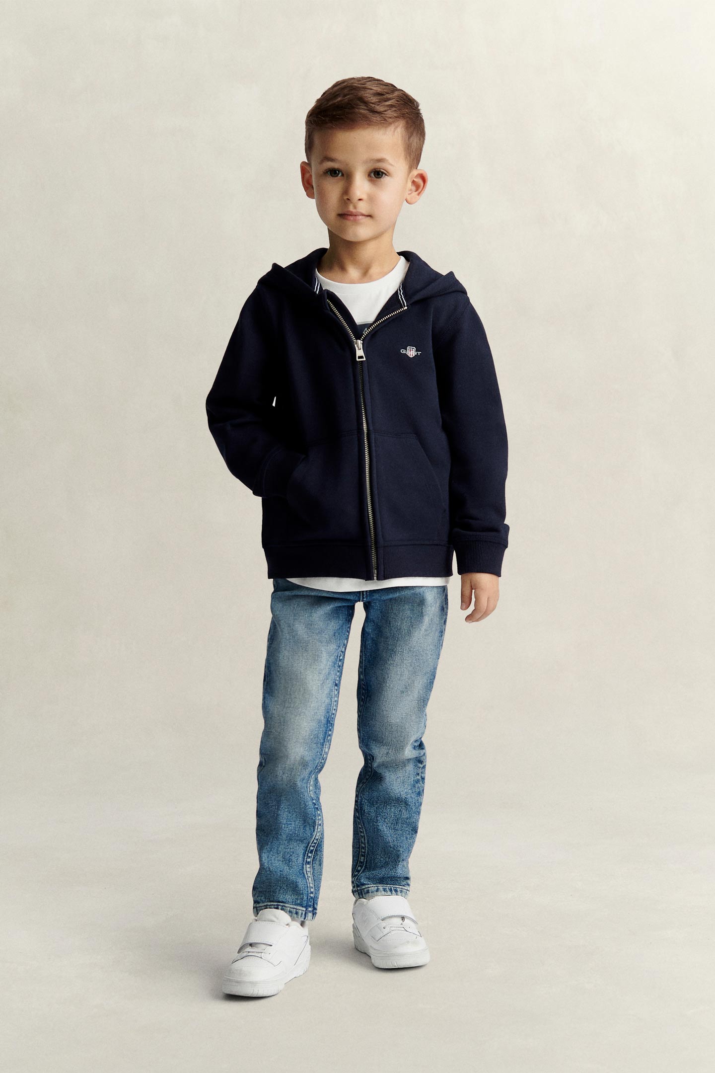 Child wearing a Gant zip-up hoodie in navy blue with front pockets and embroidered logo.
