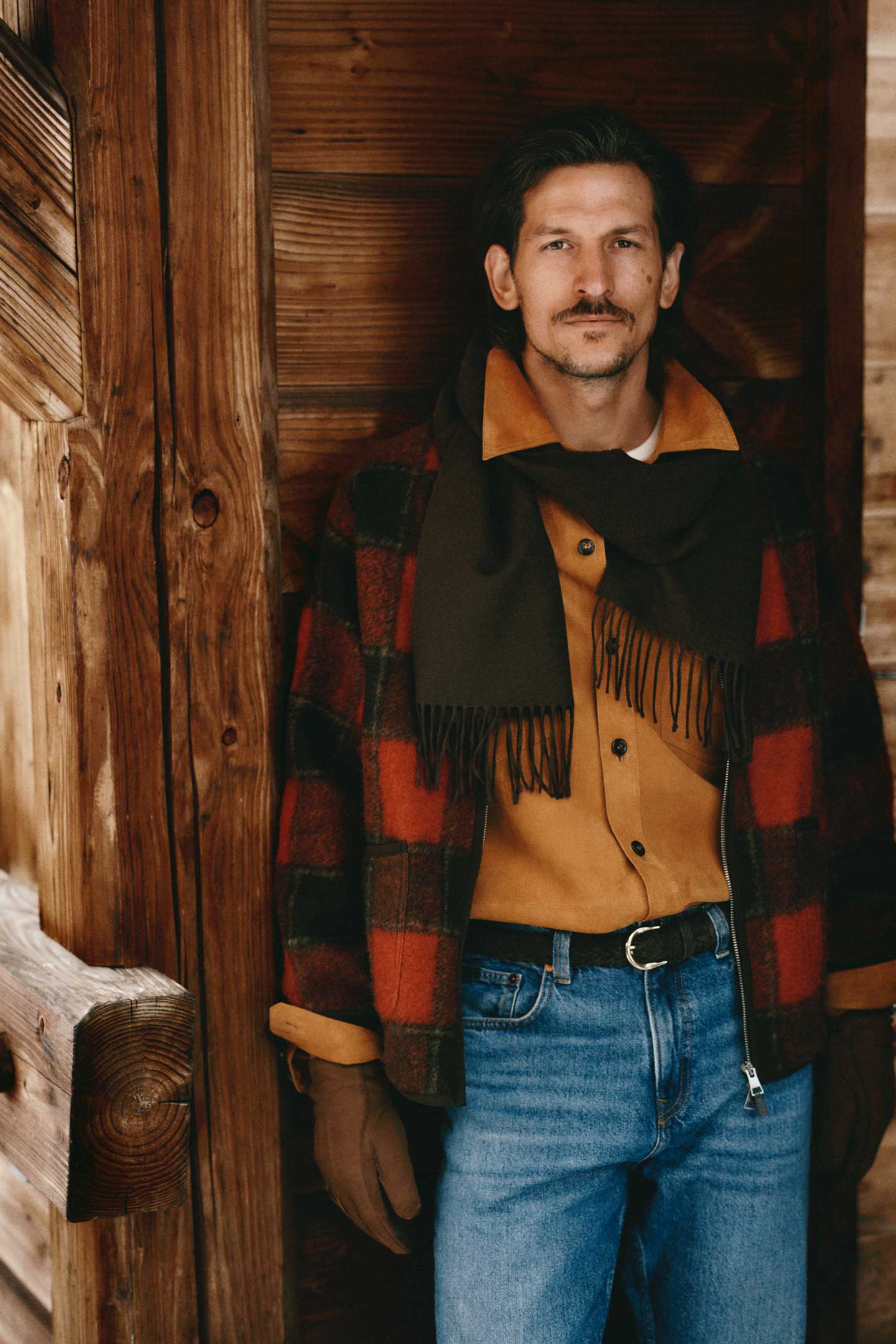 Model styled in a Gant checked wool jacket layered over a shirt and scarf, paired with jeans and gloves.