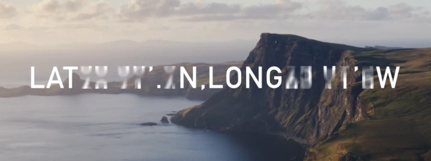 A view of the coastline of the Isle of Skype, showing the rock face of a cliff and the sea meeting it at the bottom. Numbers click across the image, eventually settling to show the latitude and longitude coordinates of the Talisker distillery.