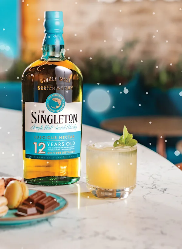 Bottle of Singleton, two delicious cocktails and a selection of macarons and dark chocolate placed on a bar counter at Singleton Distillery