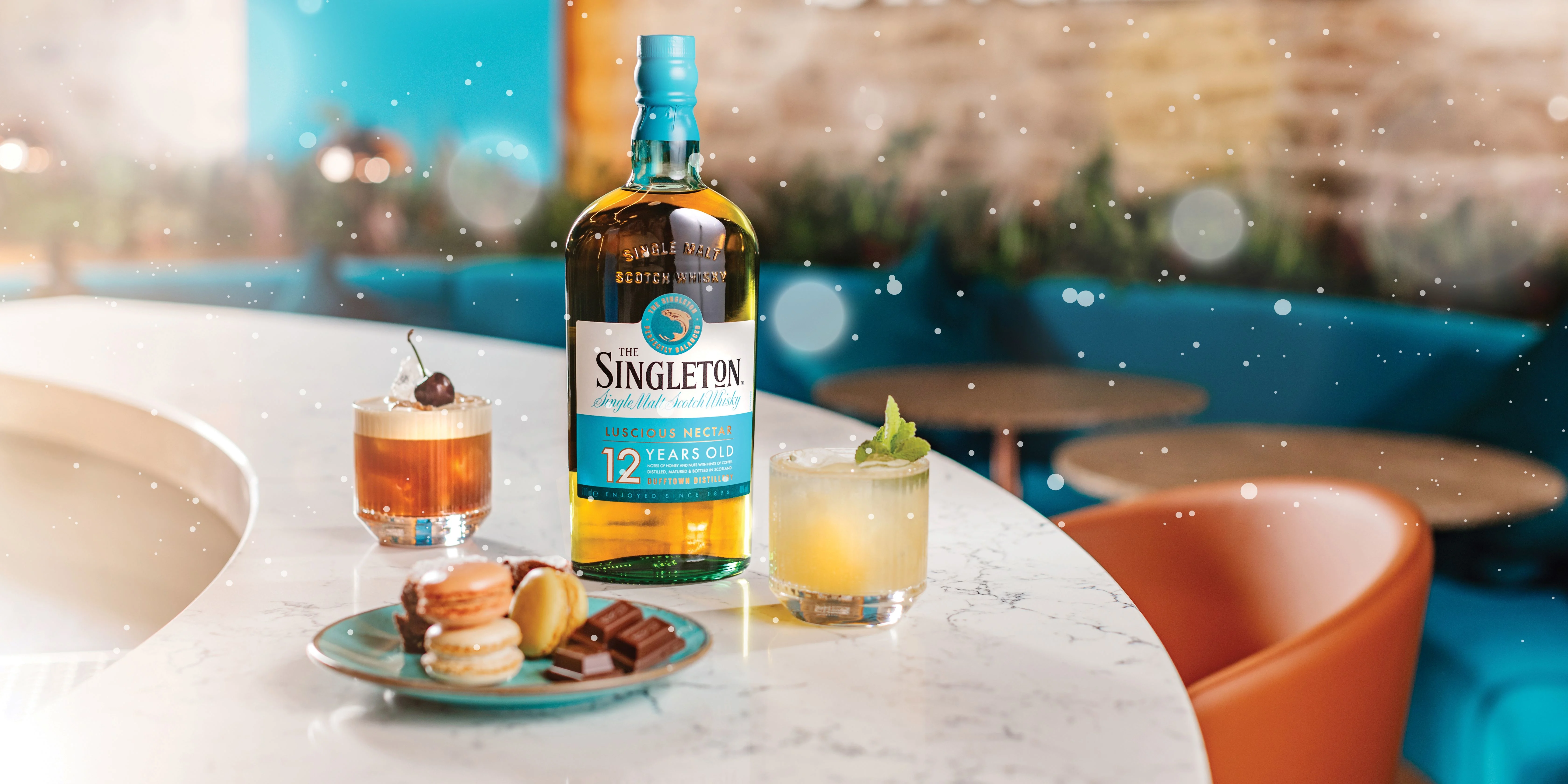 Bottle of Singleton, two delicious cocktails and a selection of macarons and dark chocolate placed on a bar counter at Singleton Distillery