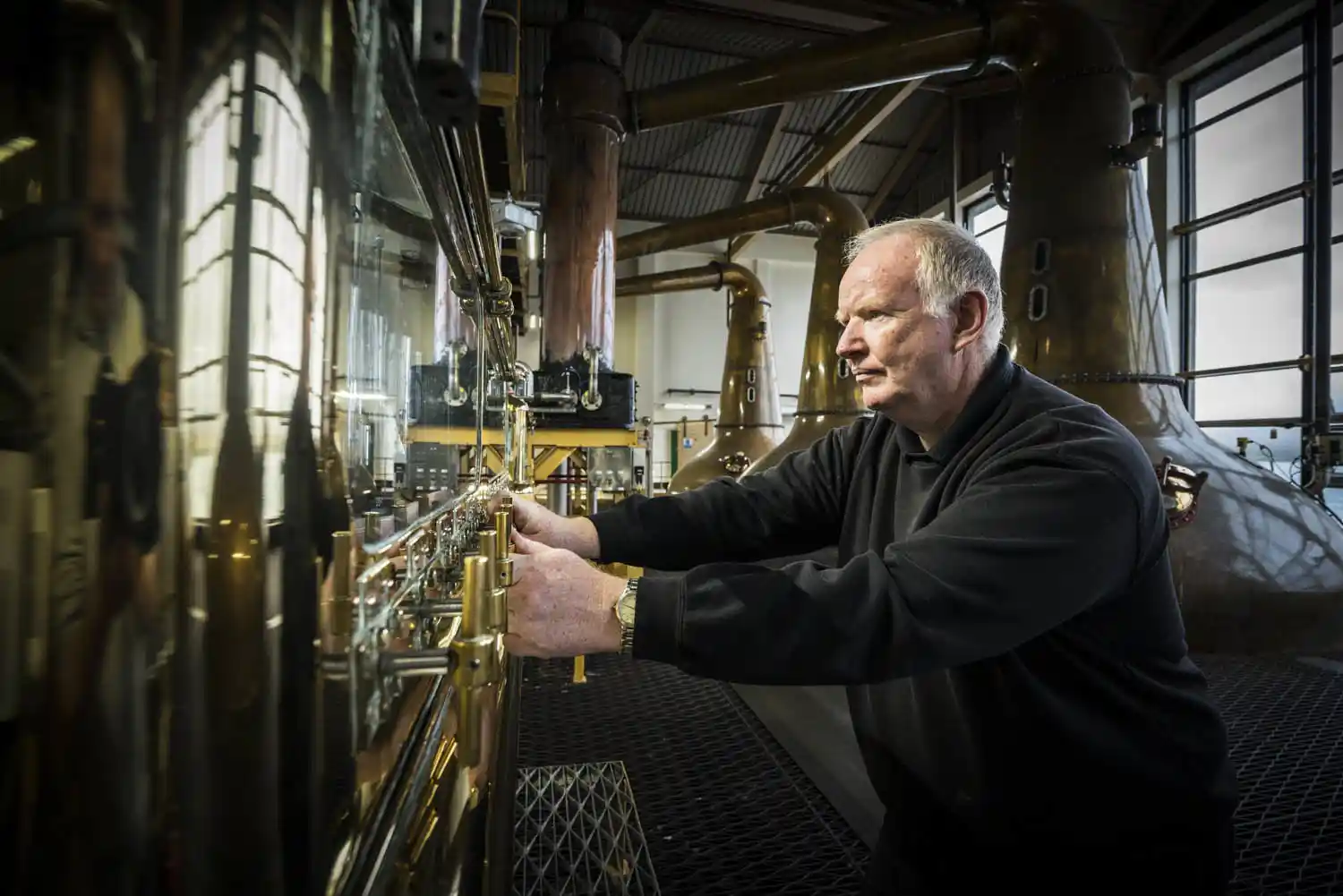 A Caol Ila employee interacts with metal whisky stills.