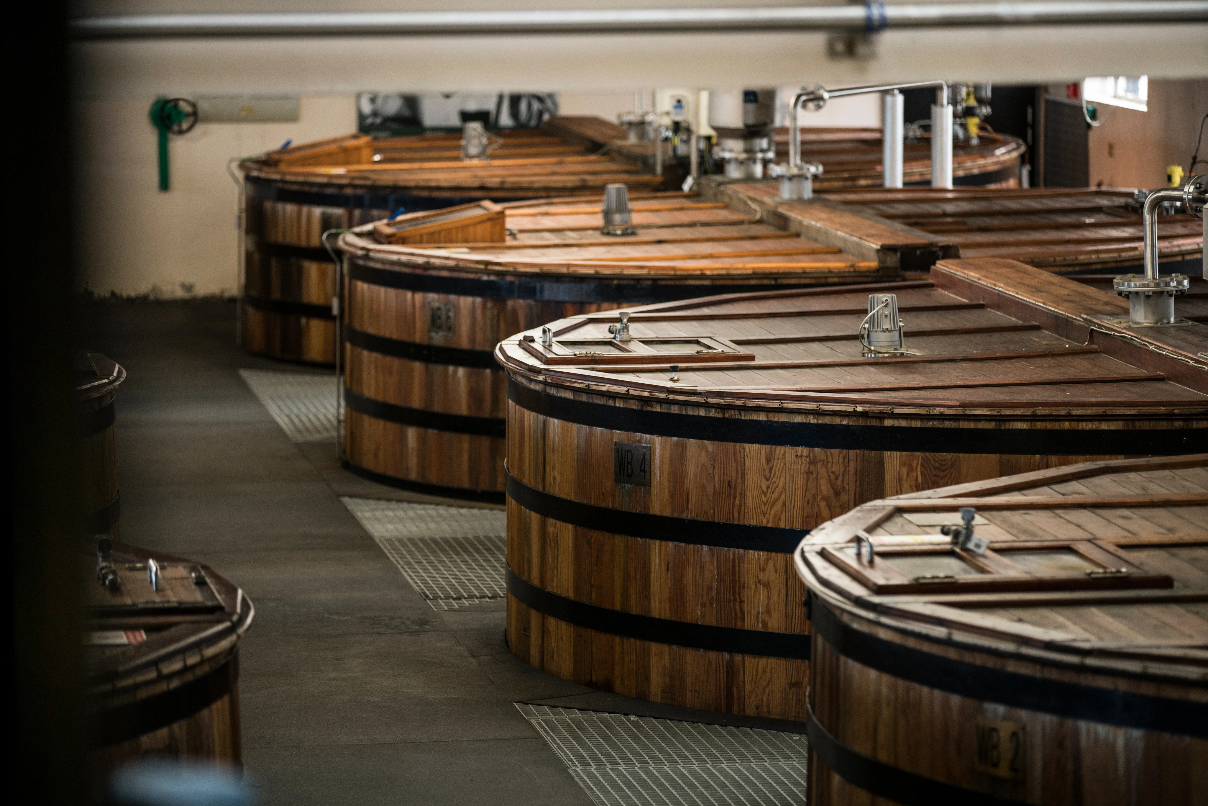 Wooden mash tuns inside a whisky distillery production room in Scotland.