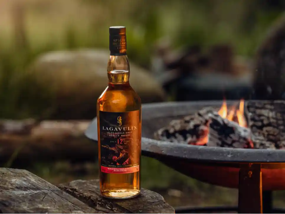 Lagavulin Fireside Tales bottle outside by a campfire 