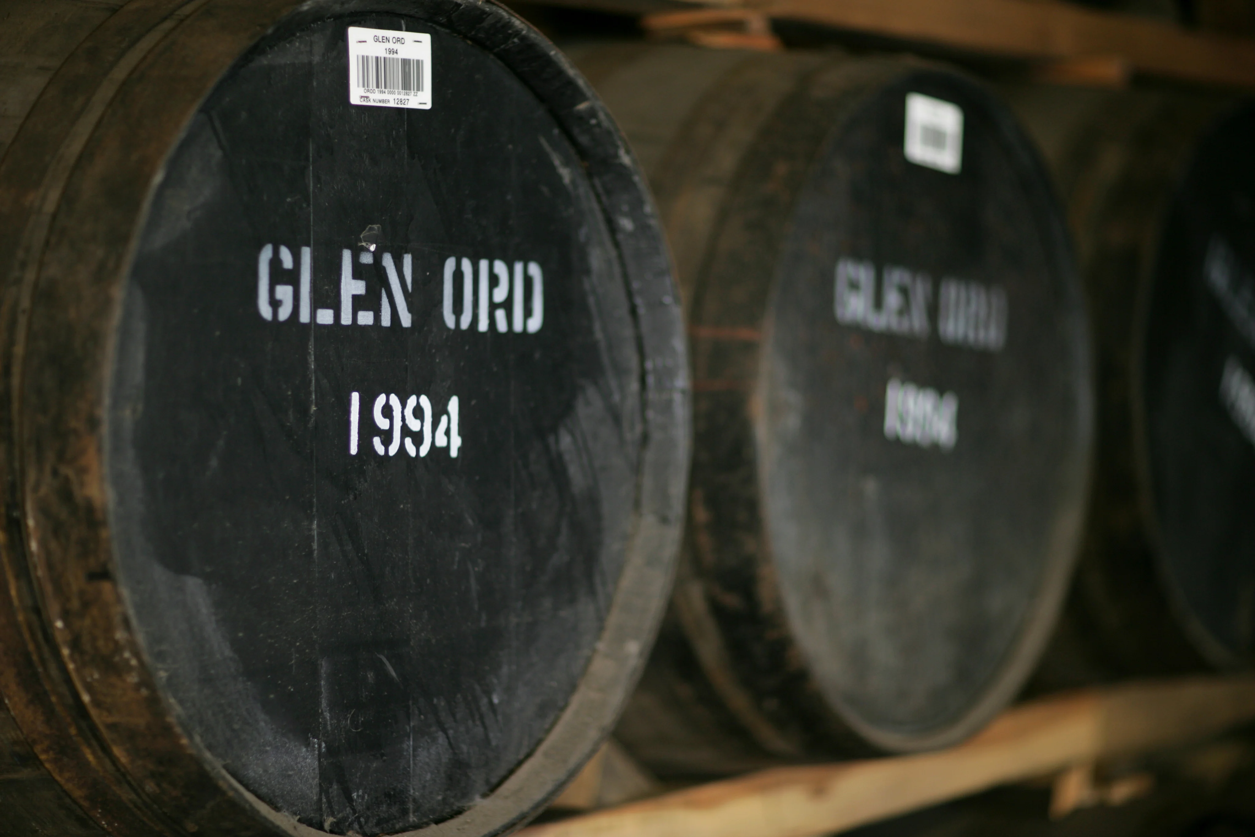 Whisky barrels marked Glen Ord 1994 inside a traditional aging warehouse.