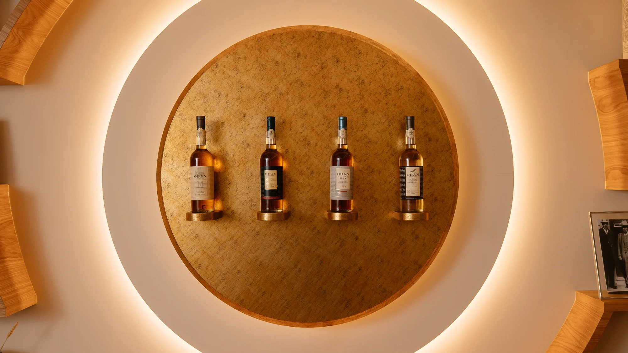 Four bottles of Oban whisky in the middle of a round illuminated background.