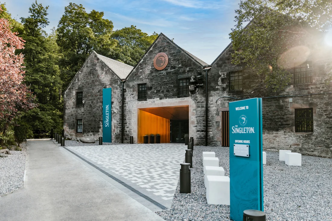 An image of the brickhouse front of the Dalwhinnie Distillery with its bronze logo at the top.