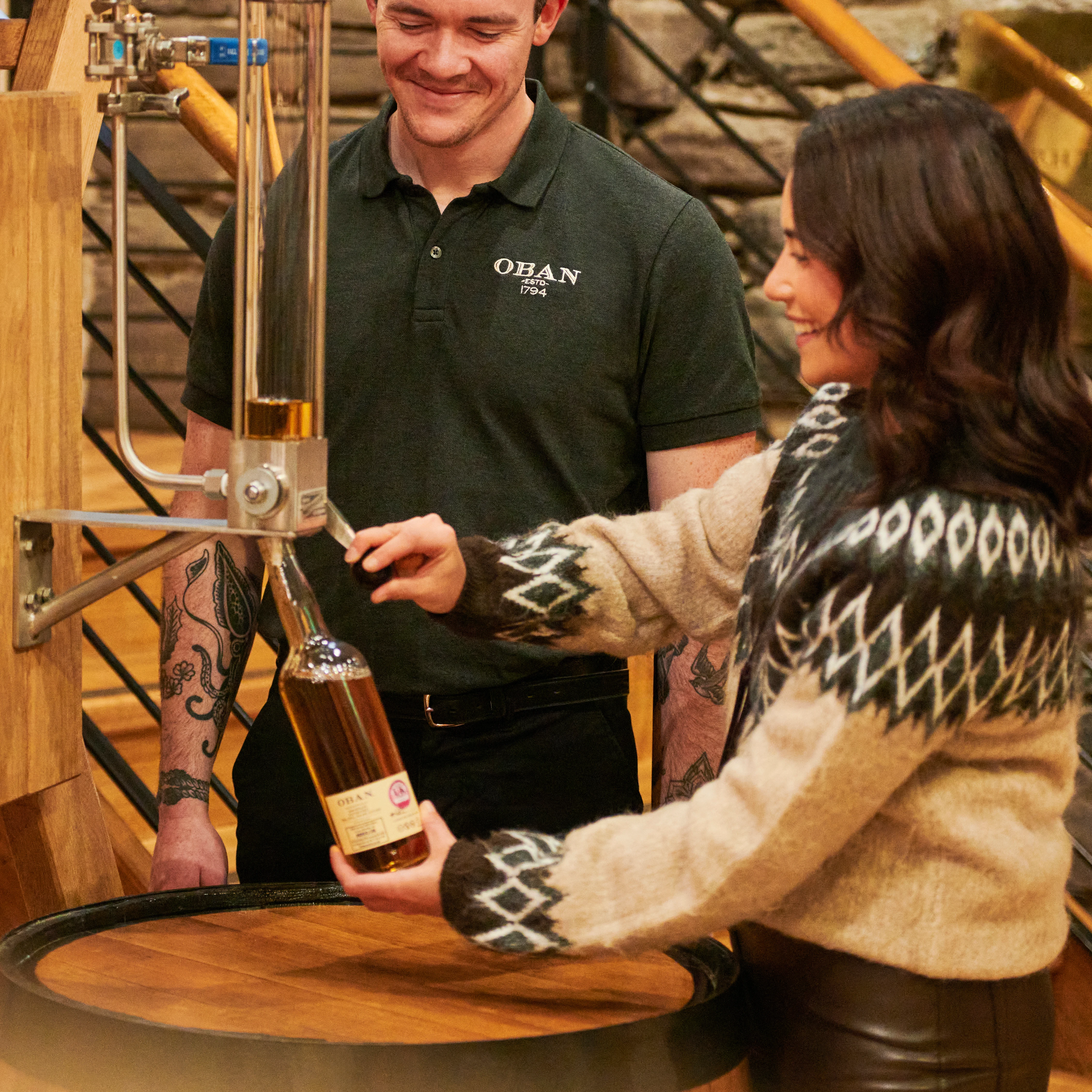 A woman pours whisky into a bottle at Oban distillery