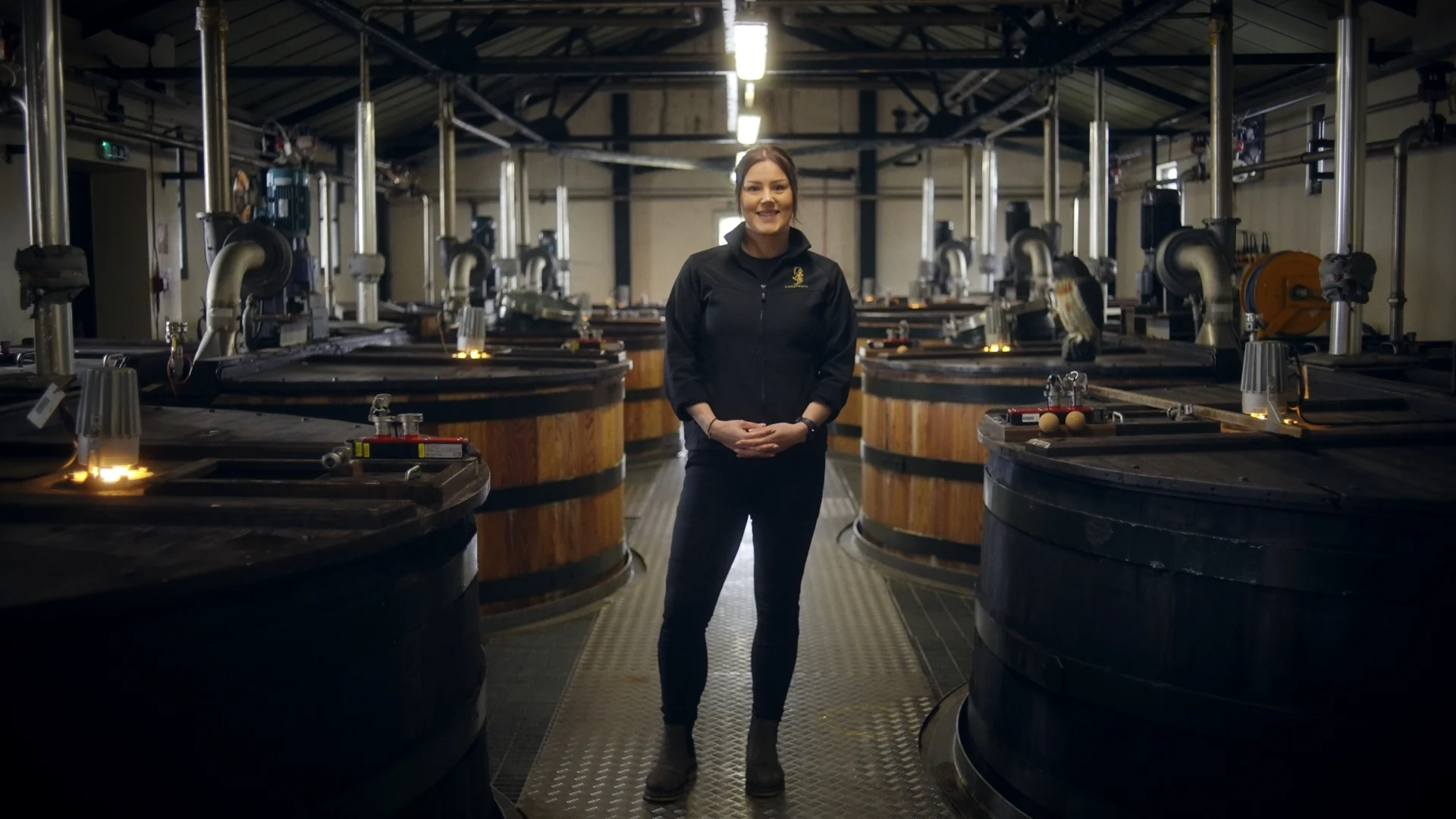 A distillery worker stands surrounded by whisky casks