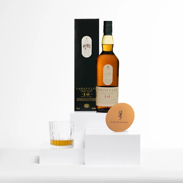 Eine Flasche Lagavulin 16 Year Old Single Malt Scotch Whisky neben einem Kupferuntersetzer mit dem Lagavulin-Logo. Beide Gegenstände befinden sich auf einer weißen Fläche.
