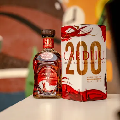 A bottle and the packaging of the 200th anniversary limited edition Cardhu Single Malt Scotch Whisky sit on a table.