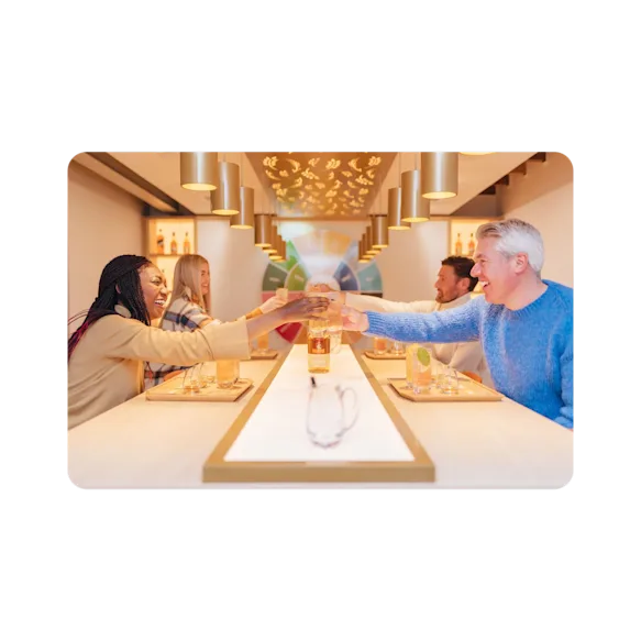 A smiling group toast Glenkinchie's finest over a well lit dining table.