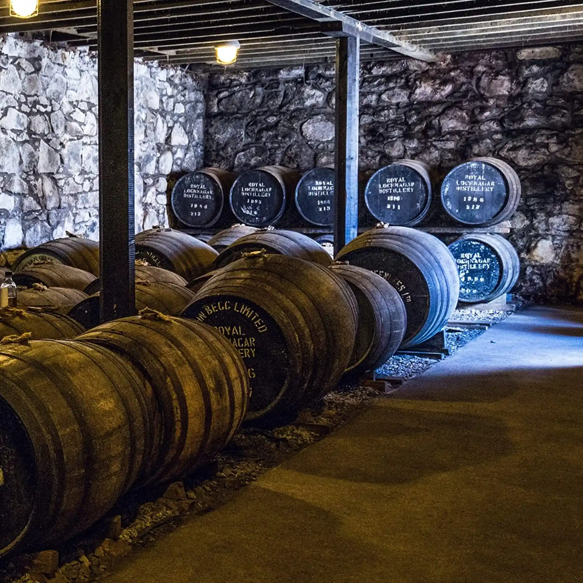 A stone storeroom with lots of wooden whisky barrels