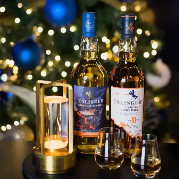 Bottle of Talisker in front of christmas tree and two small glasses of whisky