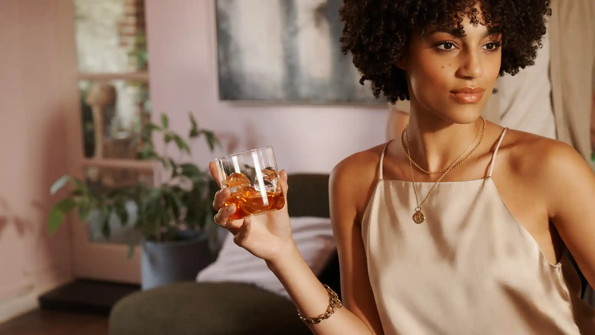 A woman holds a rocks glass of whisky and ice