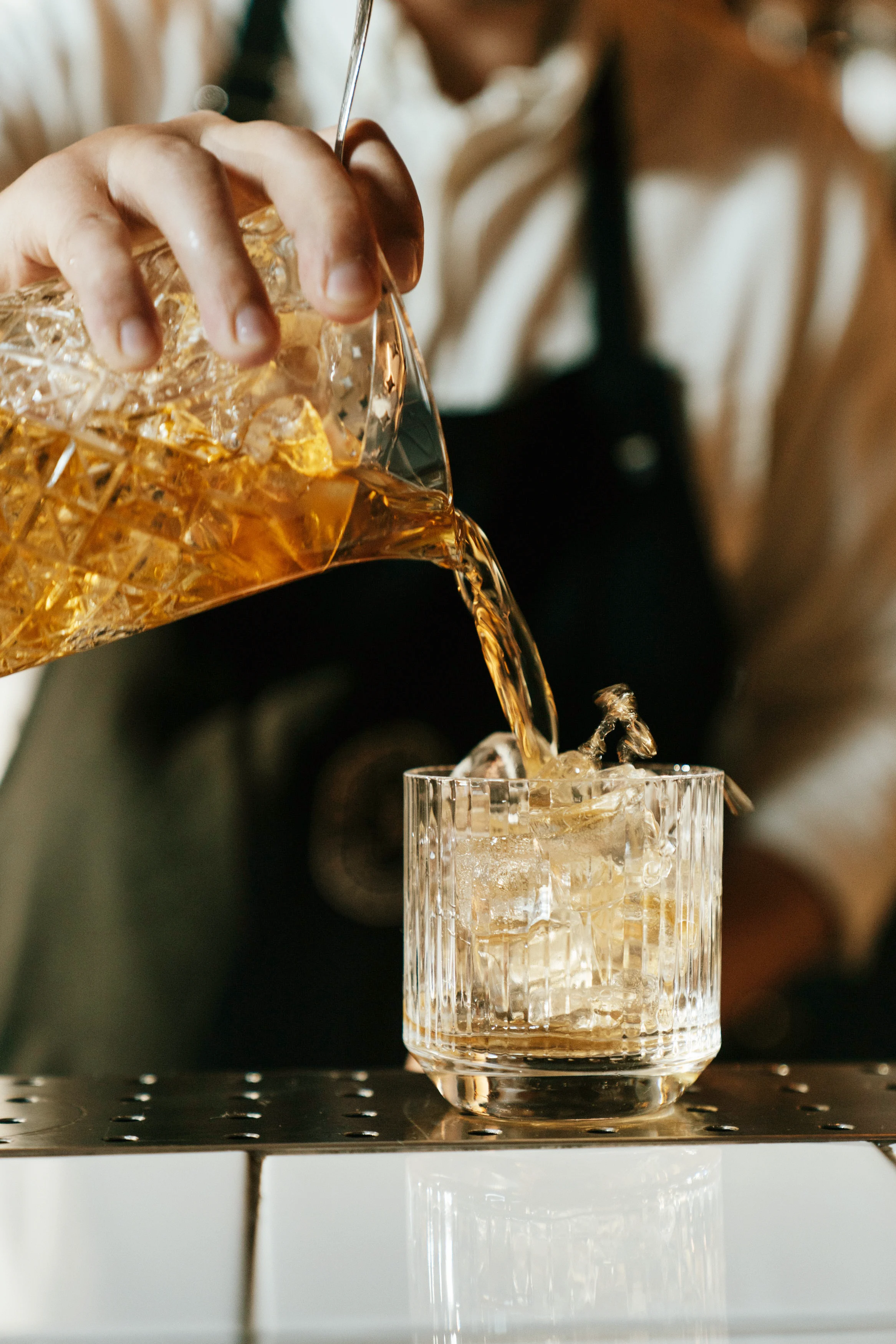 Sazerac cocktail being poured into whisky glass