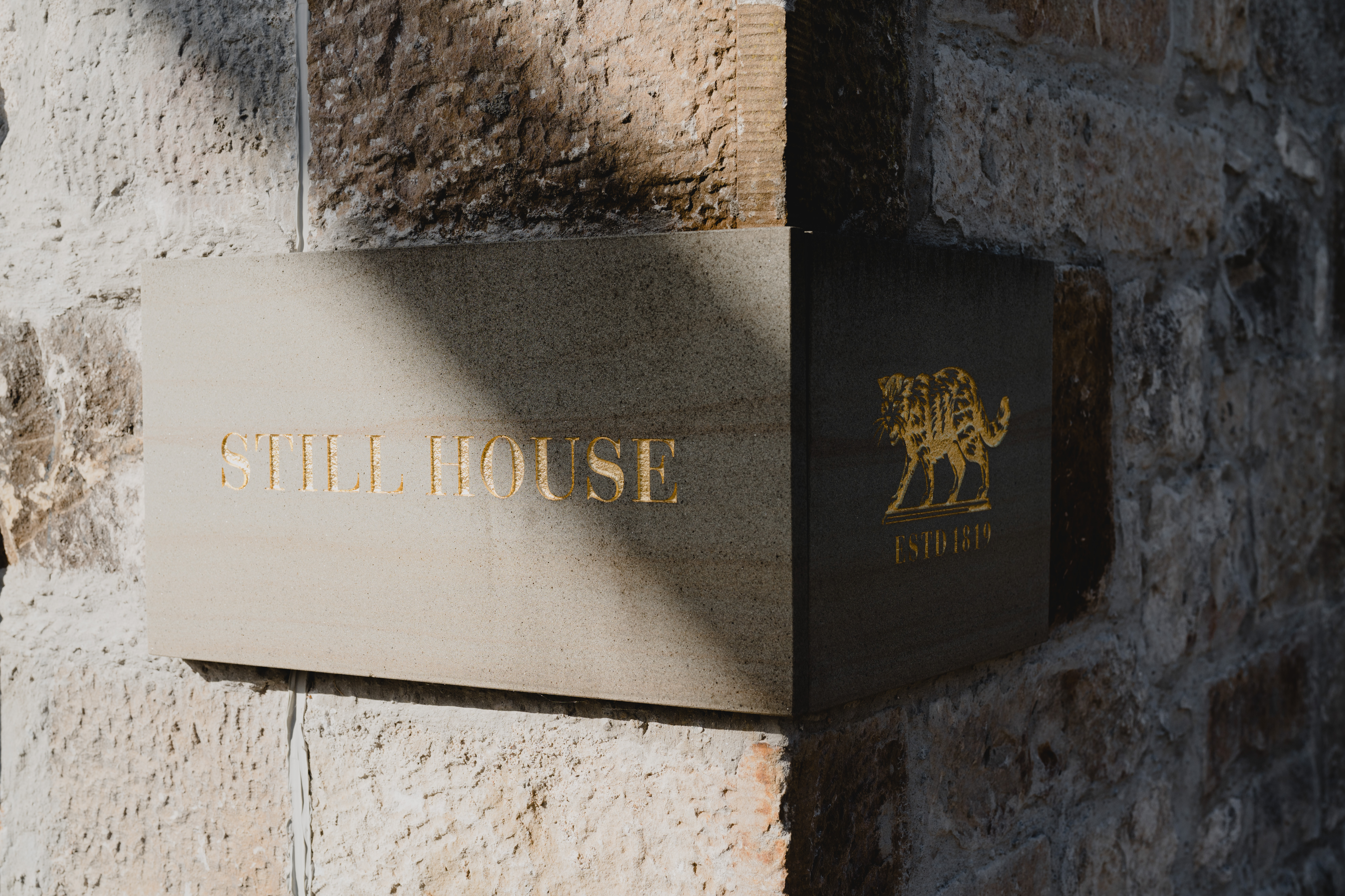The Brora wildcat logo and the words "STILL HOUSE" are embossed in gold writing on a sign on the the old, brick walls of the distillery.