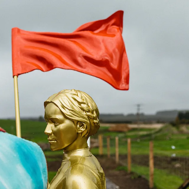 A golden statue of a Helen Cumming holding aloft a red flag, standing next to a statue of Johnnie Walker in a colourful jacket and top hat