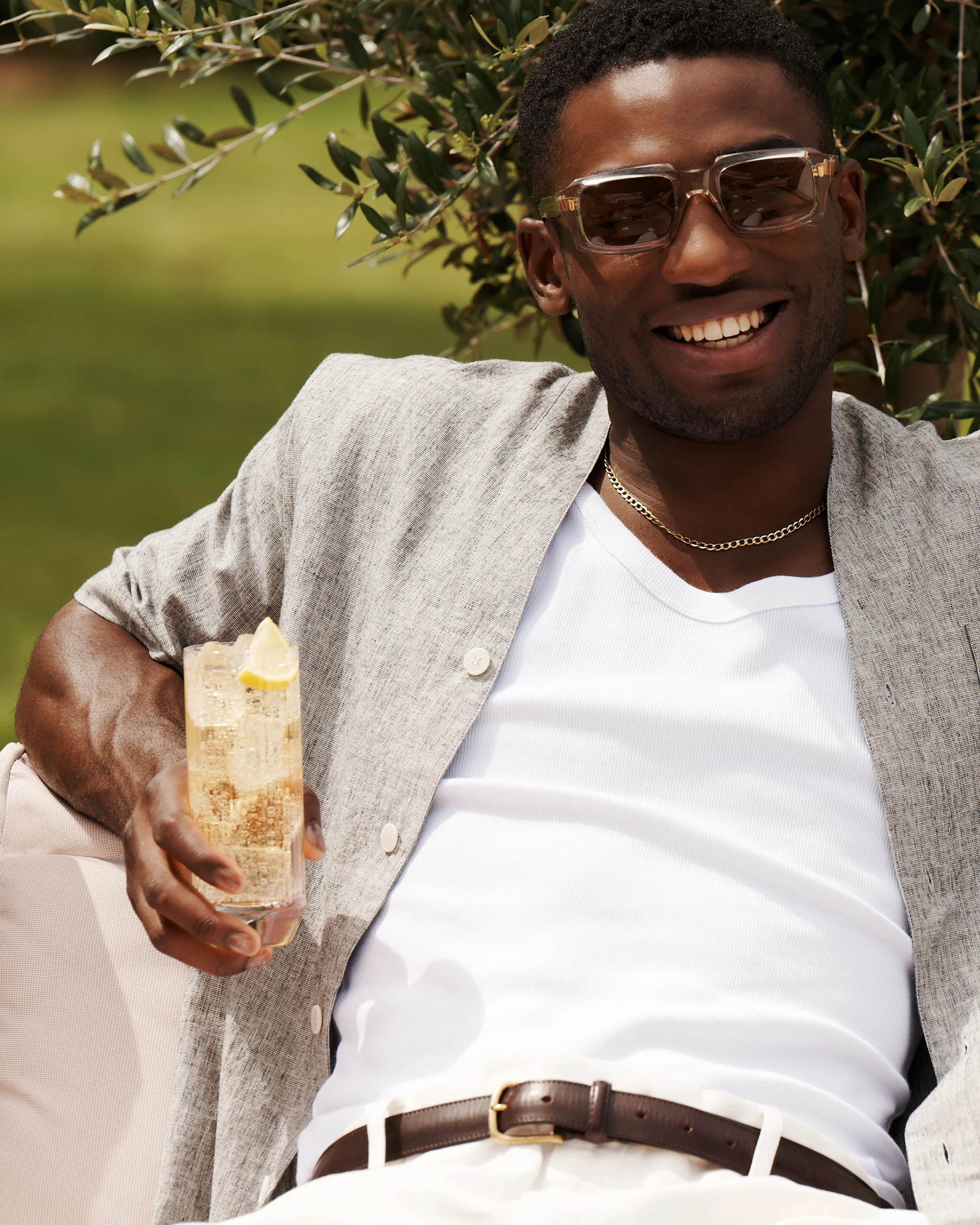 Ein Mann hält einen Whisky-Highball-Cocktail in der Hand, während er draußen in einem Garten sitzt