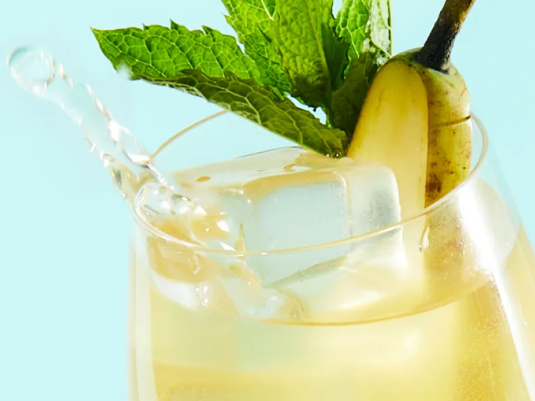 Een cocktail met een garnering van peer en munt