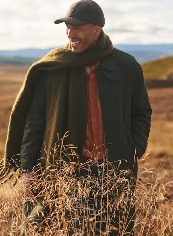 A man stand on a Highland hill, looking out into the distance