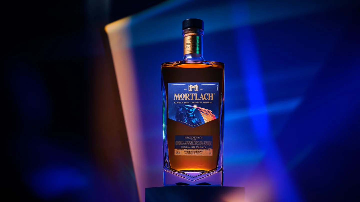 Een fles Mortlach single malt Scotch whisky staat op een sokkel voor een gouden en blauwe achtergrond.
