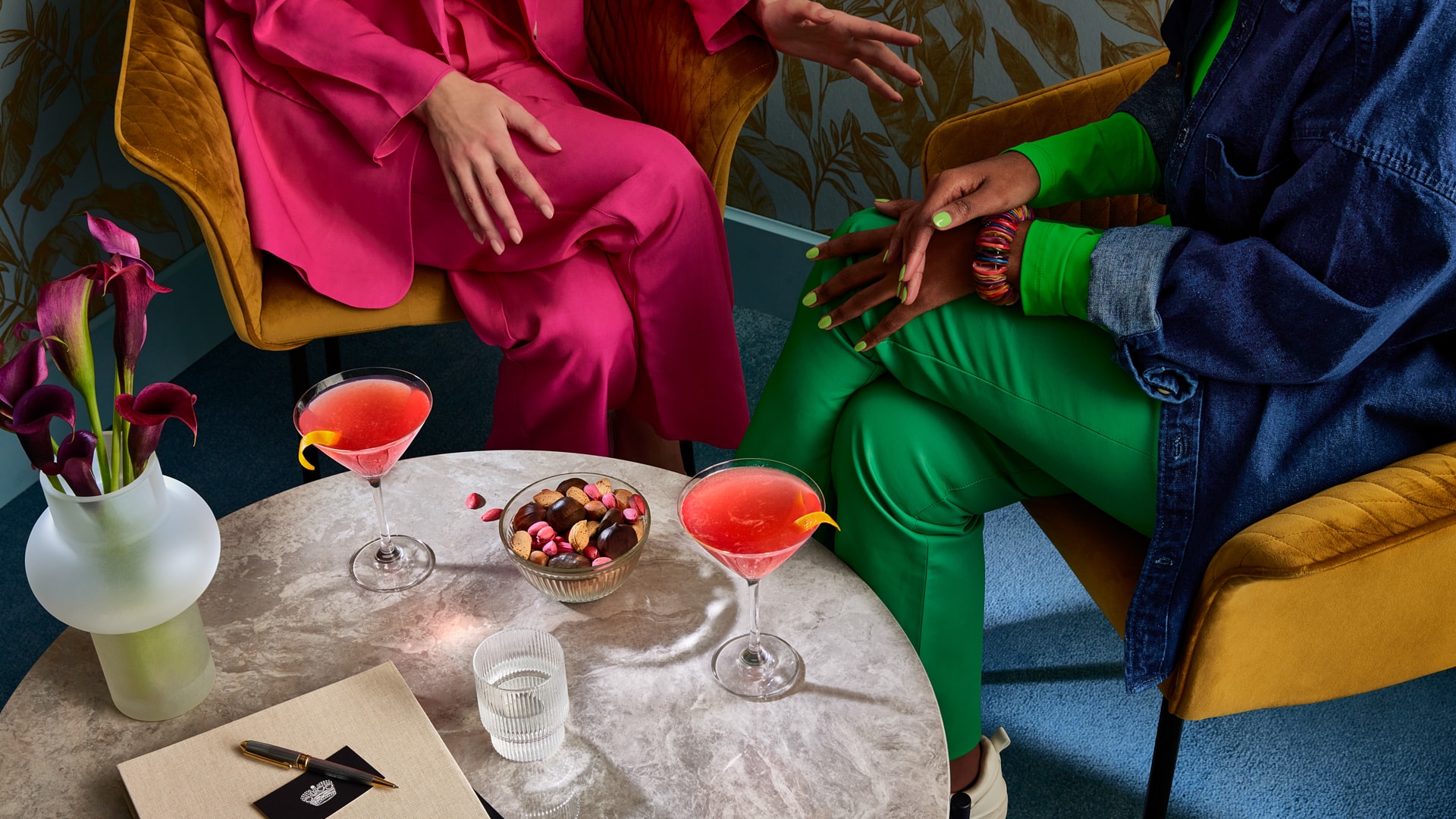 Zwei Freunde in Sesseln mit kosmopolitischen Cocktails auf dem Couchtisch vor ihnen