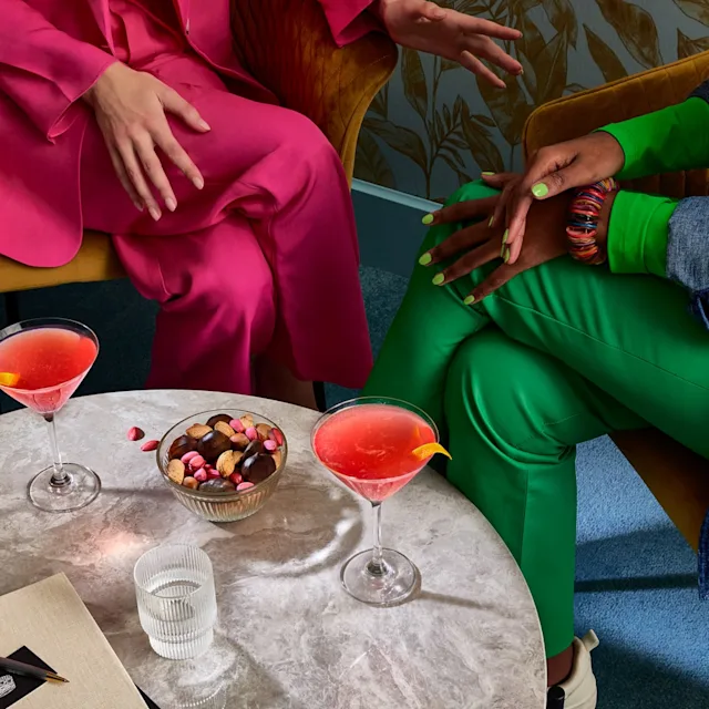 Twee vrienden in stoelen met cosmopolitan cocktails op de salontafel voor hen