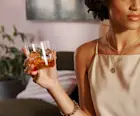 A woman holds a rocks glass or whisky and ice