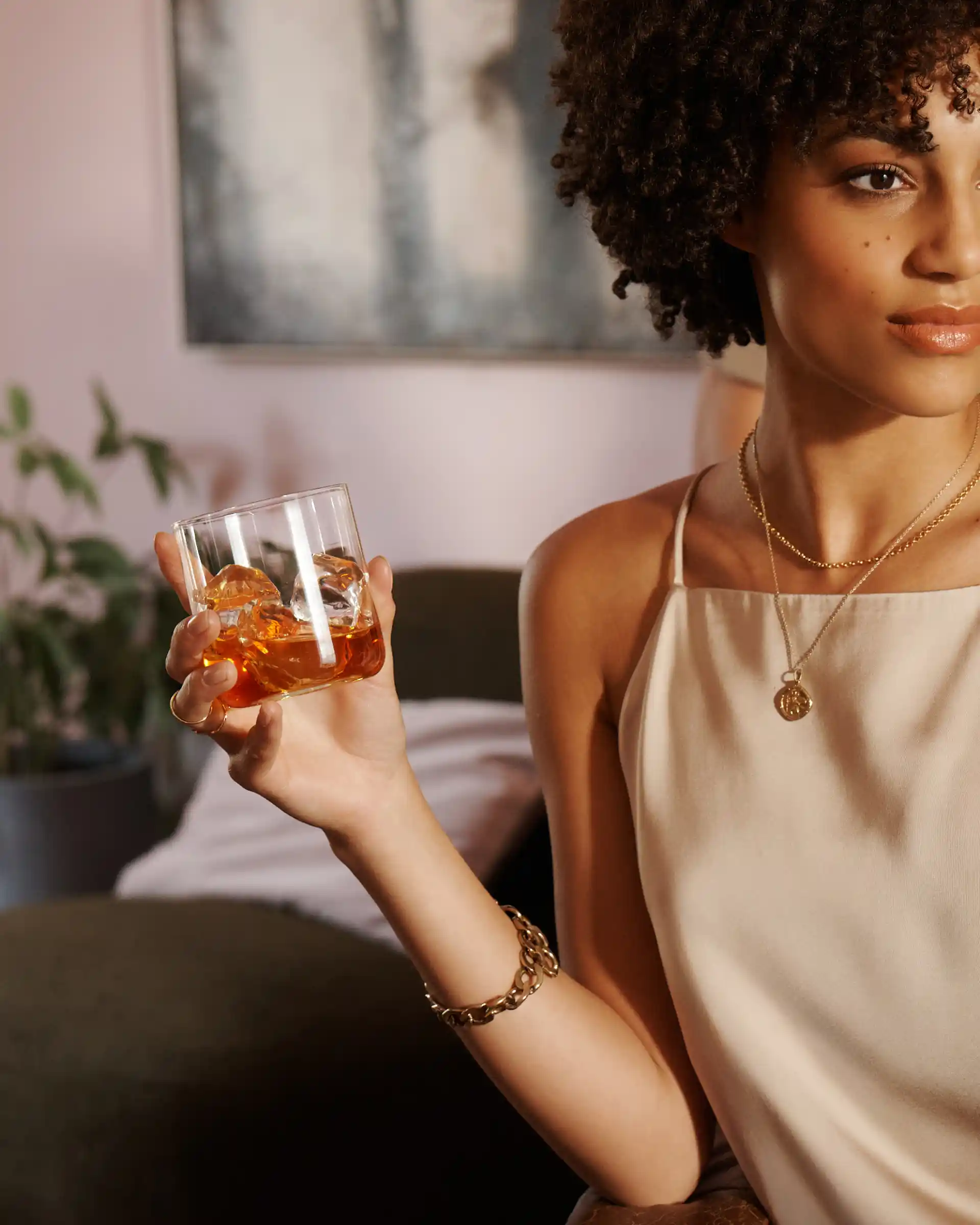 A woman holds a rocks glass or whisky and ice