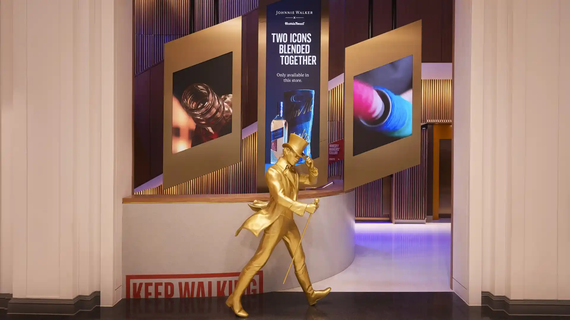 Eine goldene Statue des Johnnie Walker "Striding Man" steht neben einer Theke mit dem roten "Keep Walking"-Logo.    