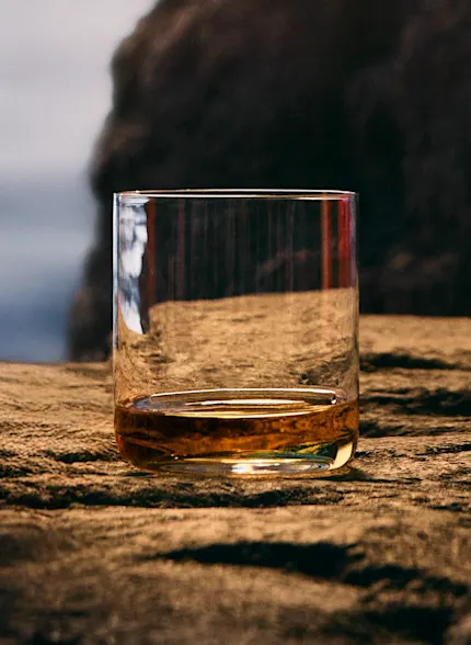 Glass of Talisker Molten Seas whisky set against a rugged backdrop