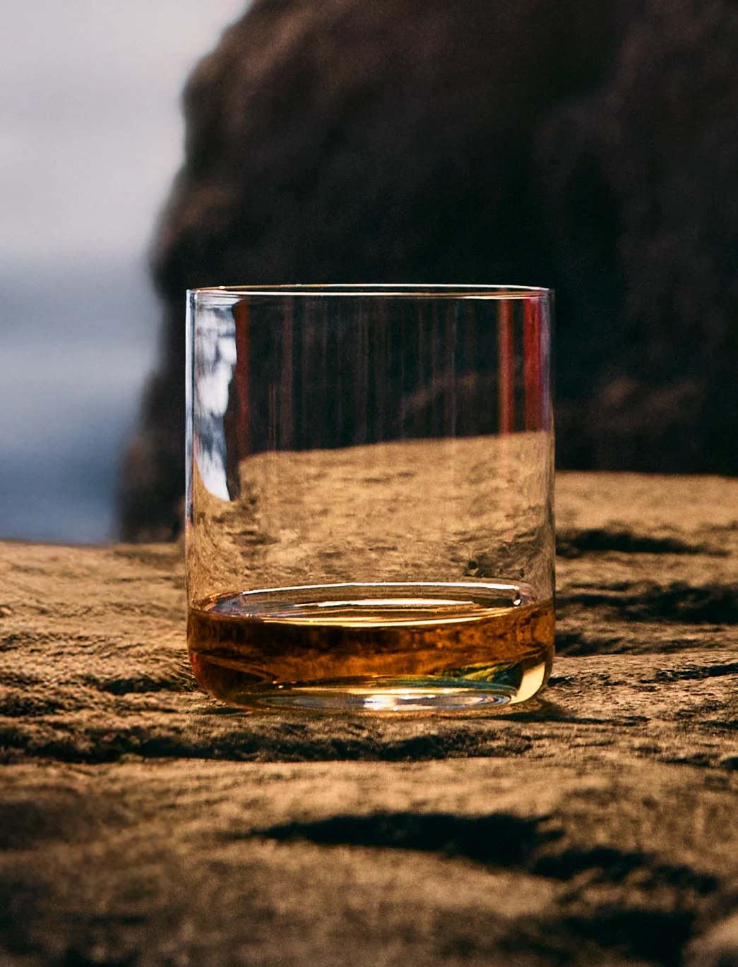 Glas Talisker Molten Seas whisky tegen een ruige achtergrond