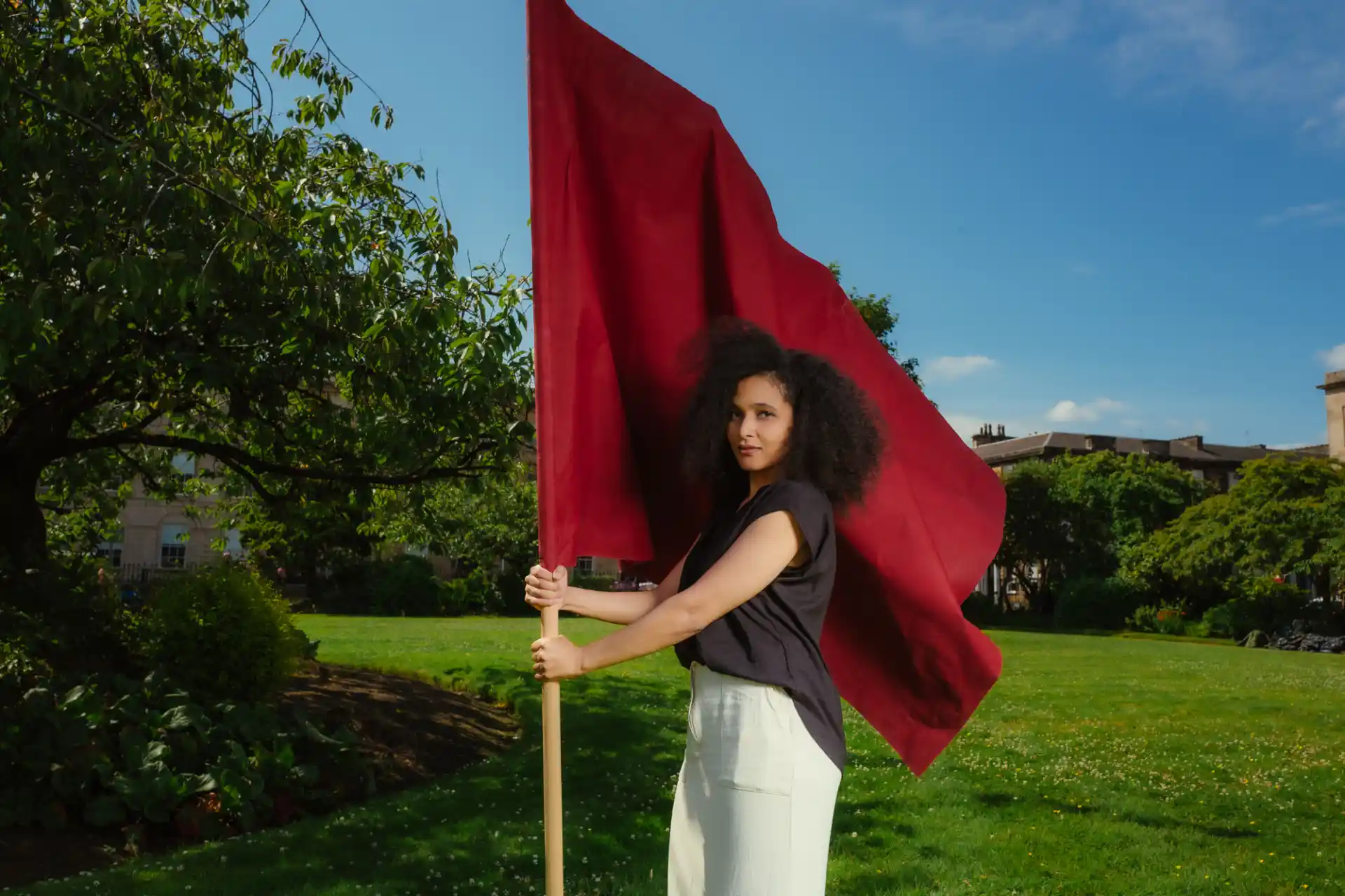 Jawahir Al-Mauly outdoors holding a red flag.