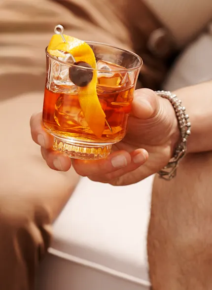 A man holds an Old Fashioned cocktail