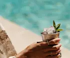 A woman holds a Mint Julep cocktail while sitting next to a pool