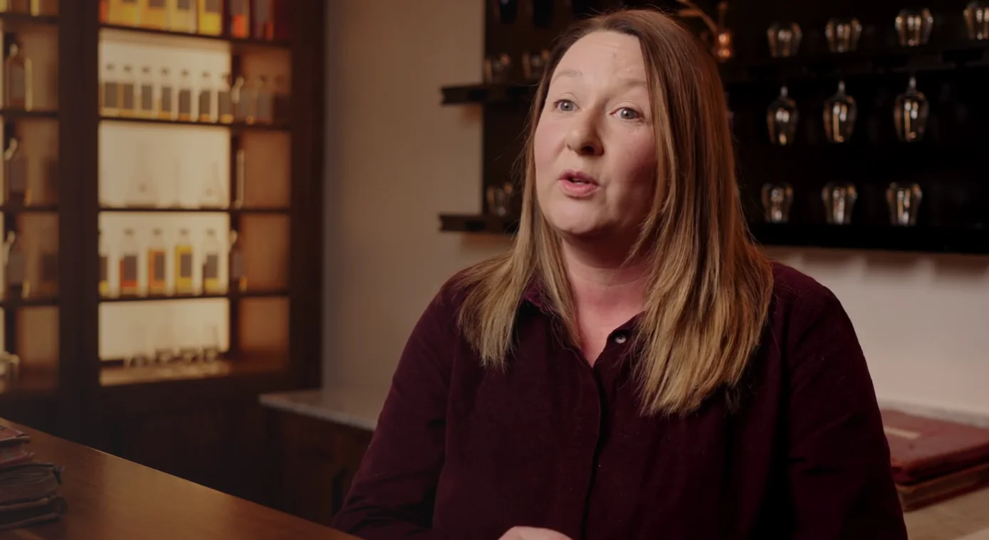 Jo sits in the Cardhu distillery in front of bottles of whisky to explain the history of Cardhu