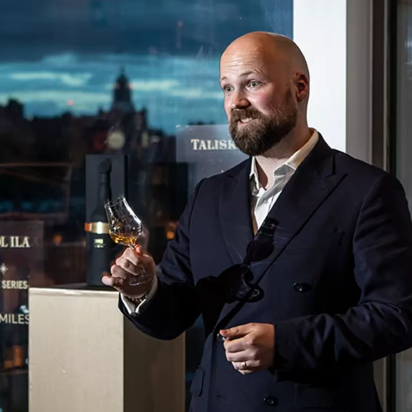 Daan van der Toorn stands at a lecturn holding a whisky tasting glass