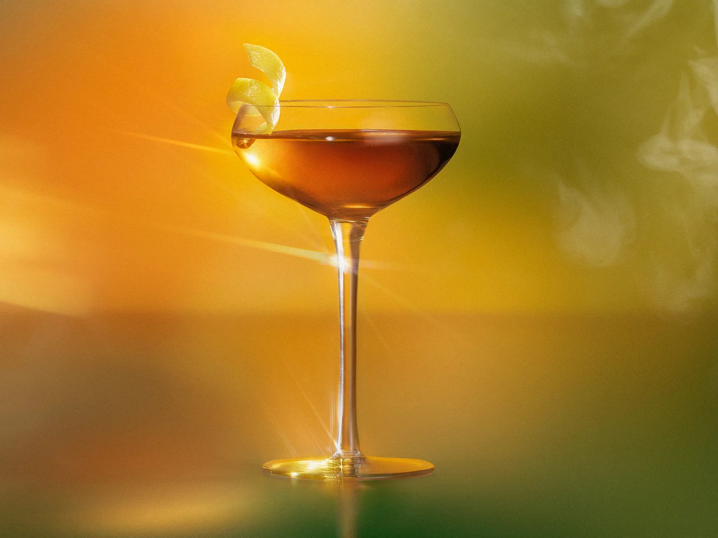 A cocktail in a coupe glass with a spiral lemon peel garnish