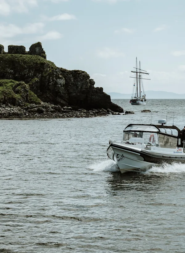 A boat sails across a body of water, with a small green island in the middle