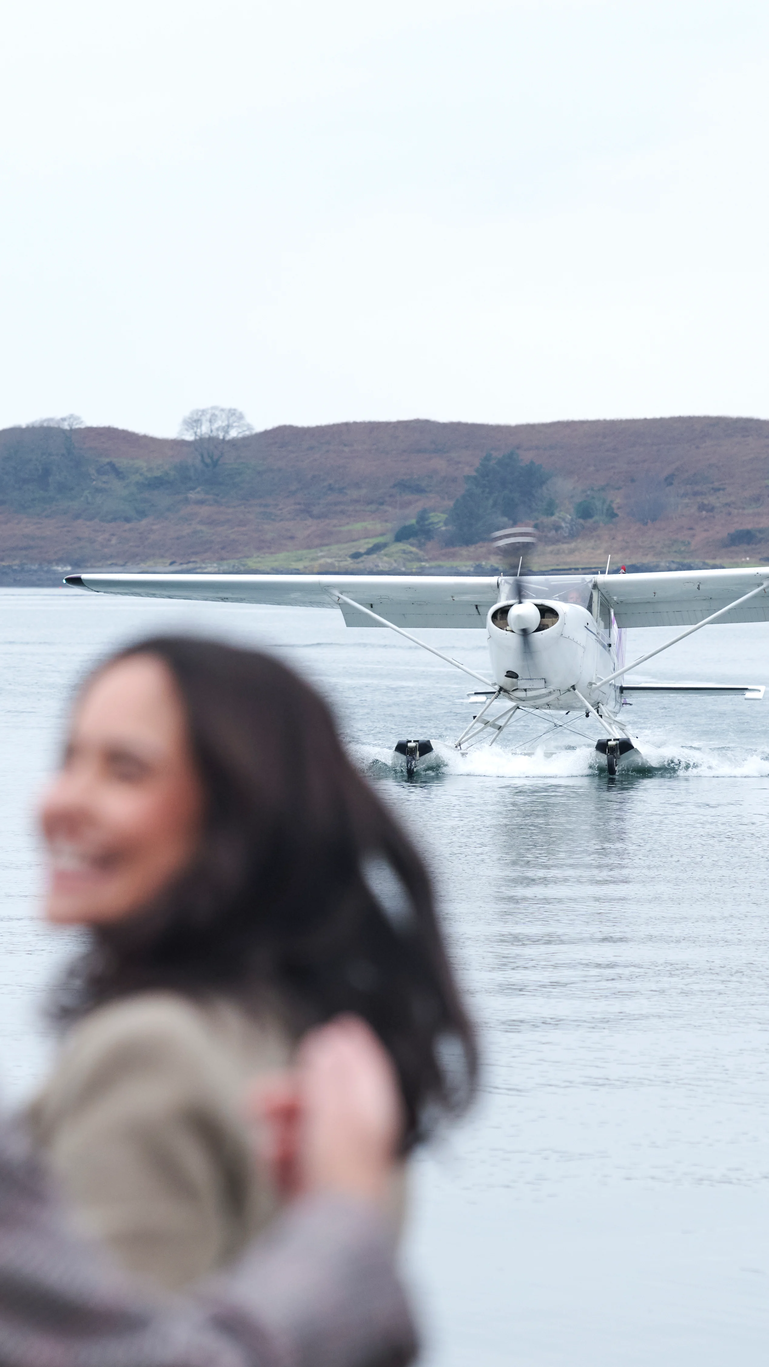A group of smiling visitors enjoying a boat trip on the waters around the Isle of Islay, with scenic Scottish coastline visible in the background
