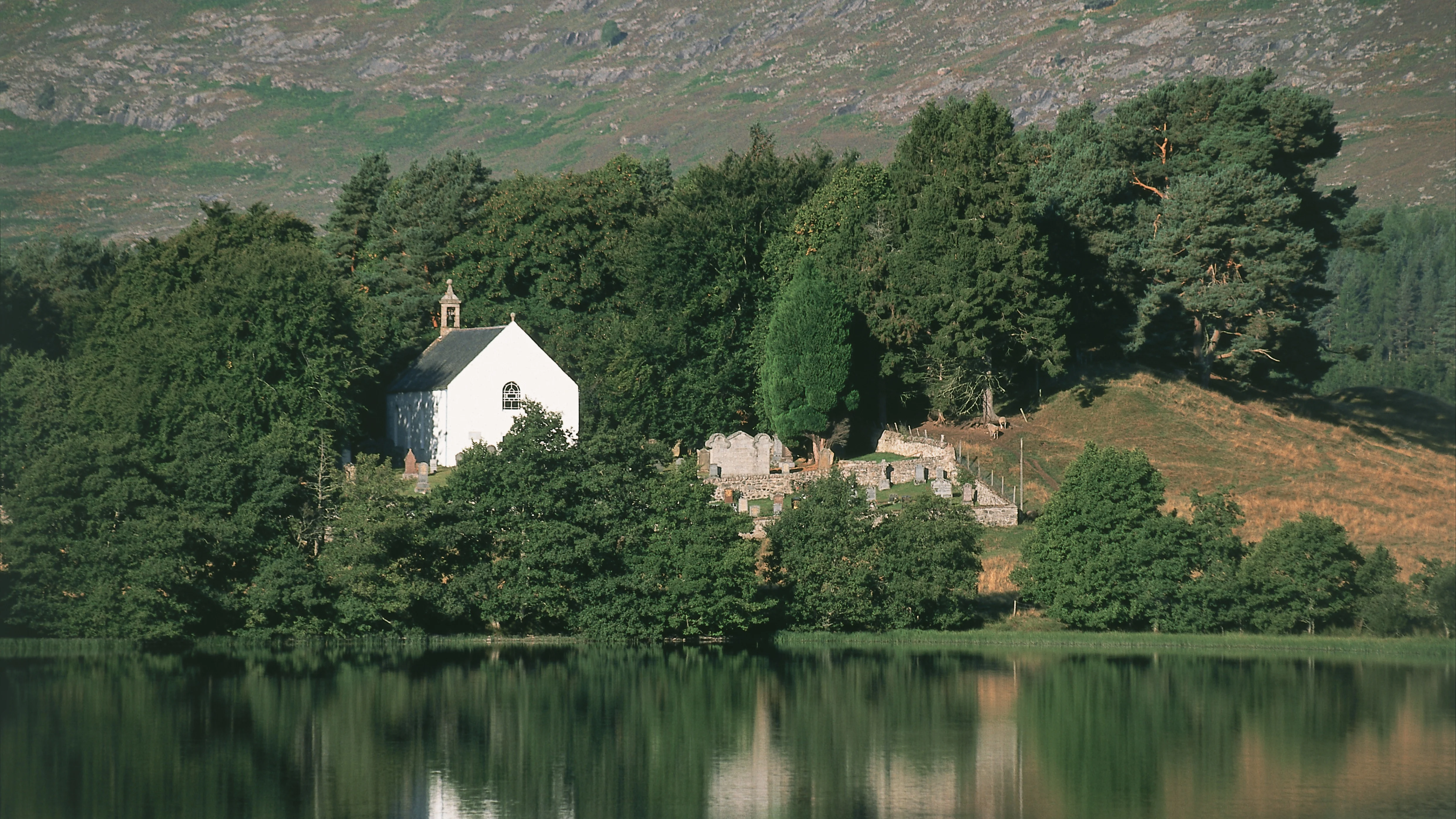 Little white church on the banks of the River Spey, surrounded by trees