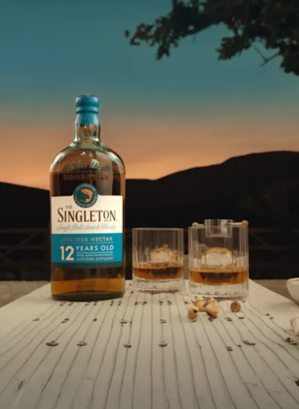 The Singleton 12-Year-Old bottle with two glasses of whiskey on a table at sunset