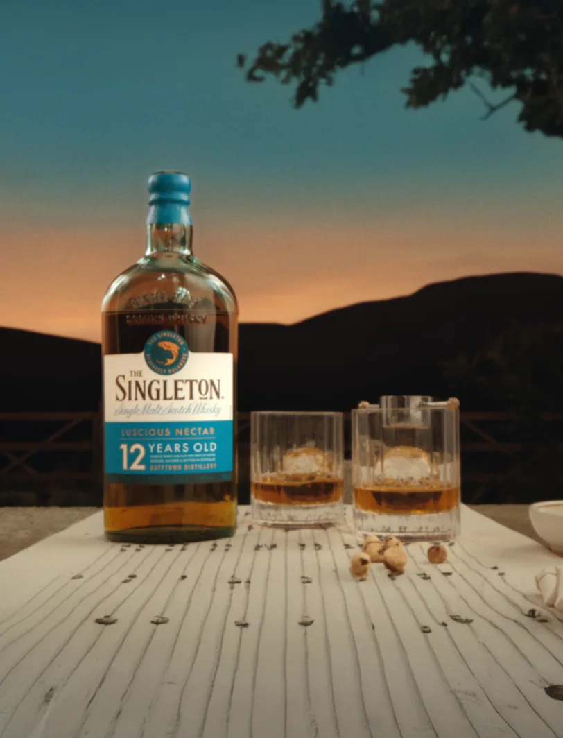 The Singleton 12-Year-Old bottle with two glasses of whiskey on a table at sunset